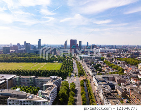 The Hague cityscape with modern and historical buildings, green areas, roads with cars driving on a sunny summer day in The Netherlands, aerial view from above 121046773