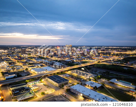 Aerial view of Birmingham, Alabama at dusk, showcasing the city's illuminated skyline and highway traffic, creating an urban nightscape with dramatic cloudy sky Aerial view of Birmingham, Alabama at dusk, showcasing the city's illuminated skyline and highway traffic, creating an urban nightscape with dramatic cloudy sky 121046810