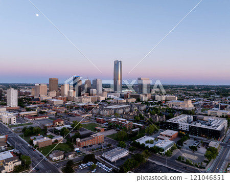 Stunning aerial sunrise view of Oklahoma City skyline with Devon Energy Center standing tall and visible moon, highlighting urban landscape and architectural marvels 121046851