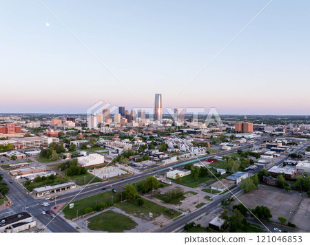 Aerial view of Oklahoma City skyline, including Devon Energy Center, glowing in the sunset with the moon overhead, highlighting urban growth and city infrastructure 121046853