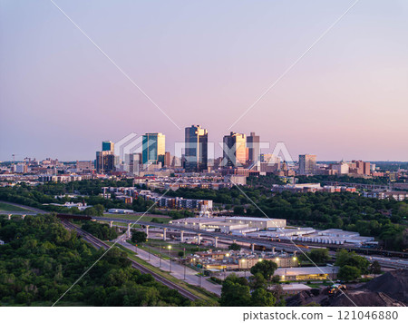 Aerial view of Fort Worth, Texas at dusk, vibrant cityscape, prominent skyscrapers, modern low residential buildings, active rail yard, and lush greenery Aerial view of Fort Worth, Texas at dusk, vibrant cityscape, prominent skyscrapers, modern low residential buildings, active rail yard, and lush greenery 121046880
