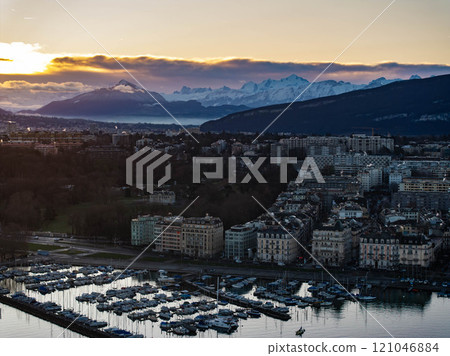 Breathtaking panoramic sunrise over Geneva city with Lake Geneva, moored boats, buildings, and snow capped Alps mountains in the background Breathtaking panoramic sunrise over Geneva city with Lake Geneva, moored boats, buildings, and snow capped Alps mountains in the background 121046884