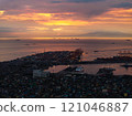 Manila's lively port area at sunset, featuring cargo ships dotted across the horizon against a dramatic sky with colorful clouds, and city lights twinkling below 121046887