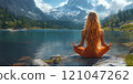 beautiful young woman is practicing yoga by the lake with a beautiful snowy mountain 121047262