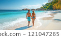 A tourist couple walks hand in hand along a beautiful beach on their honeymoon. 121047265