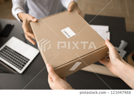 Delivery office employee giving parcel to customer 121047988
