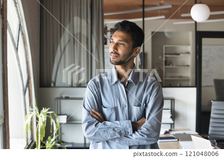 Indian business man standing with arms crossed with thoughtful expression 121048006