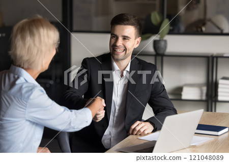 Two young and mature colleagues finish meeting with handshake gesture 121048089
