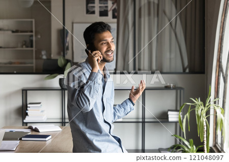Young Indian businessman engaged in work-related discussion on smartphone 121048097