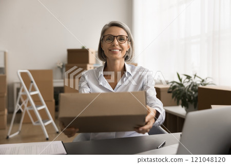 Happy successful businesswoman giving cardboard paper box 121048120