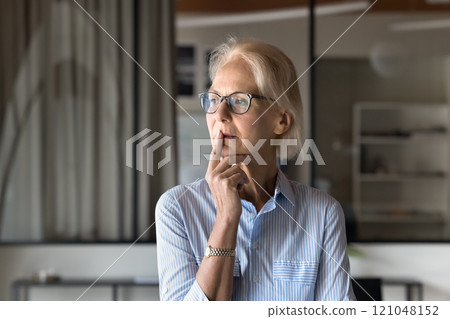 Mature woman with thoughtful expression, looks into distance 121048152