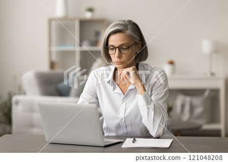 Serious mature business woman in glasses working at laptop Serious mature business woman in glasses working at laptop 121048208