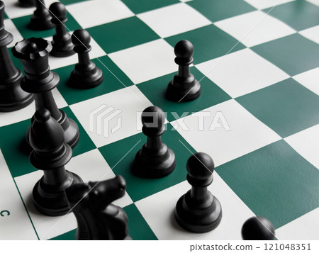 Strategic chess game on green and white board with black pieces 121048351