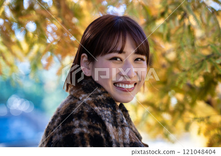 A young woman with a short bob enjoying autumn leaves 121048404