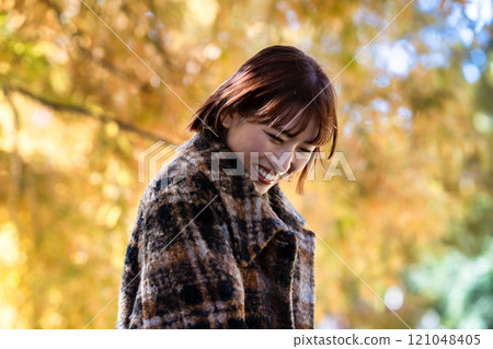 一位留著短鮑勃的年輕女子正在欣賞秋葉 121048405