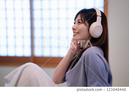 Middle-aged woman listening to music in a Japanese-style room Middle-aged woman listening to music in a Japanese-style room 121048448