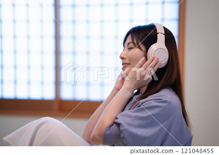 Middle-aged woman listening to music in a Japanese-style room Middle-aged woman listening to music in a Japanese-style room 121048455