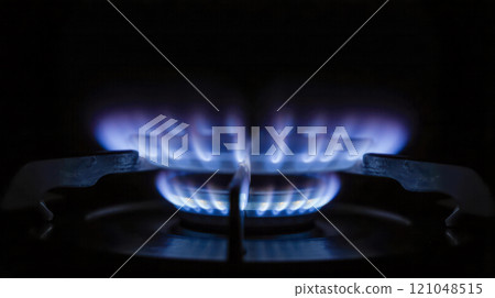 Blue gas flame on kitchen burner in dark setting, representing high energy costs, natural gas usage, household heating expenses, energy crisis, cooking fuel consumption Blue gas flame on kitchen burner in dark setting, representing high energy costs, natural gas usage, household heating expenses, energy crisis, cooking fuel consumption 121048515