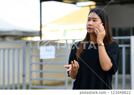 Young asian woman talking on mobile phone in a bright, urban environment Young asian woman talking on mobile phone in a bright, urban environment 121048622