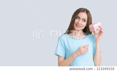 Present party. Holiday surprise. Special day festive greeting. Curious happy woman in blue guessing gift in box isolated on light copy space. 121049159