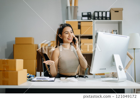 Young business owner woman prepare parcel box and standing check online orders for deliver 121049172