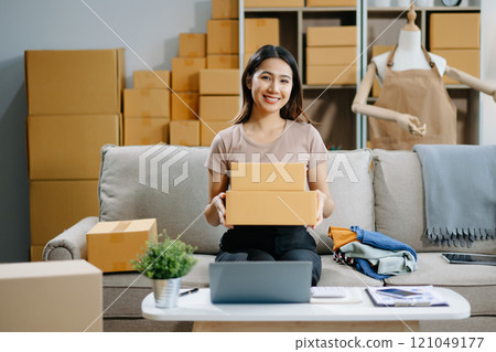 Young business owner woman prepare parcel box and standing check online orders for deliver Young business owner woman prepare parcel box and standing check online orders for deliver 121049177