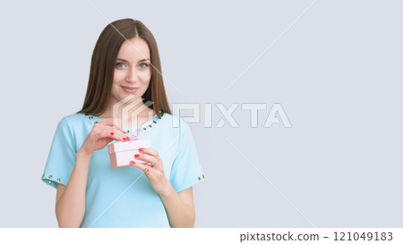 Party fun. Festive joy. Smiling satisfied beautiful happy woman in blue with present in box isolated on light copy space background. 121049183