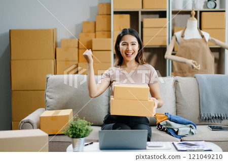 Young business owner woman prepare parcel box and standing check online orders for deliver 121049210