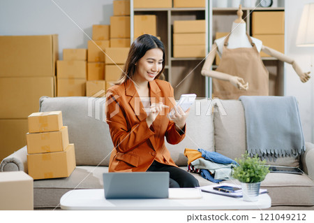 Young business owner woman prepare parcel box and standing check online orders for deliver 121049212