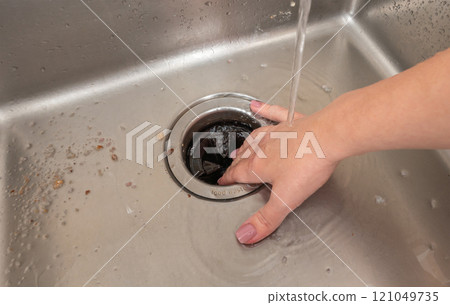 The danger of placing a hand into a running garbage disposer in a kitchen sink. The danger of placing a hand into a running garbage disposer in a kitchen sink. 121049735