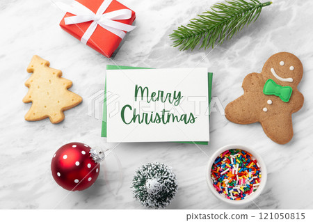 Merry Christmas card and green envelope with gingerbread man, red gift box and christmas decoration on marble table Merry Christmas card and green envelope with gingerbread man, red gift box and christmas decoration on marble table 121050815