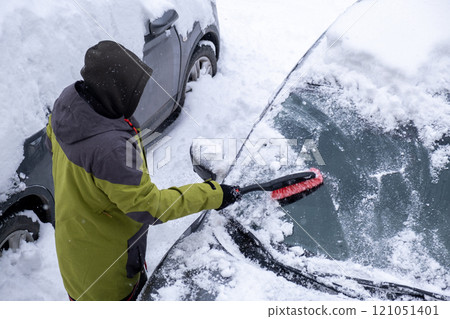 Person Clearing Snow from Car in Winter Landscape Person Clearing Snow from Car in Winter Landscape 121051401
