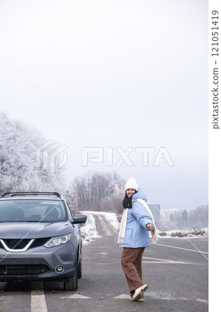 Woman in Winter Clothing by SUV on Snowy Road 121051419