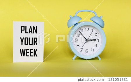 The phrase PLAN YOUR WEEK on a notepad and a yellow background with a clock The phrase PLAN YOUR WEEK on a notepad and a yellow background with a clock 121051881