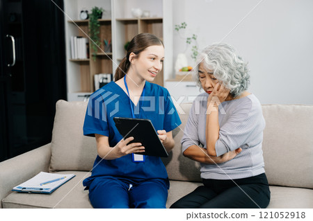 Doctors explain the use of medication to patients. Medical doctor holing senior patient's hands and comforting her on sofa 121052918