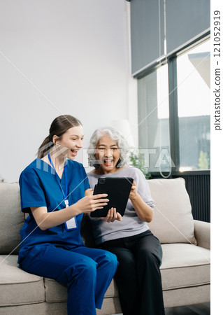Doctors explain the use of medication to patients. Medical doctor holing senior patient's hands and comforting her on sofa 121052919