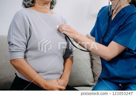 Young nurse helping elderly woman walk in the room, holding his hand, supporting. Treatment and rehabilitation after injury in assisted living facility Young nurse helping elderly woman walk in the room, holding his hand, supporting. Treatment and rehabilitation after injury in assisted living facility 121053247