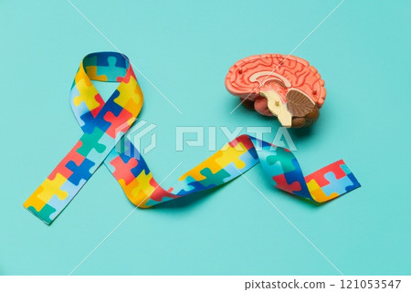 World Autism awareness and pride day. Anatomical model human brain with Puzzle pattern ribbon on blue background. World Autism awareness and pride day. Anatomical model human brain with Puzzle pattern ribbon on blue background. 121053547