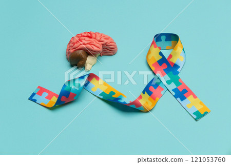 World Autism awareness and pride day. Anatomical model human brain with Puzzle pattern ribbon on blue background. World Autism awareness and pride day. Anatomical model human brain with Puzzle pattern ribbon on blue background. 121053760
