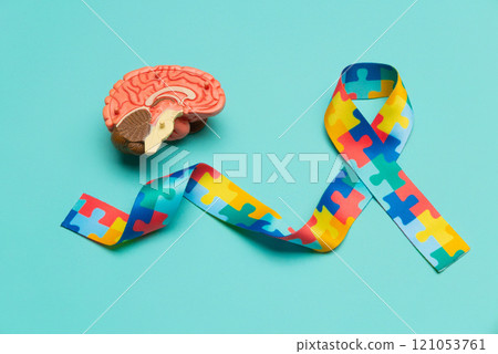 World Autism awareness and pride day. Anatomical model human brain with Puzzle pattern ribbon on blue background. World Autism awareness and pride day. Anatomical model human brain with Puzzle pattern ribbon on blue background. 121053761