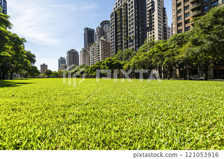 Low-angle view of green park space and modern buildings on both sides in downtown Taichung, Taiwan, It is near the National Taichung Theater. 121053916