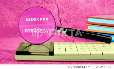 Business planning concept. BUSINESS STRATEGY written on the glass of the magnifying glass 121054077