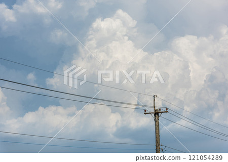 View of utility poles with blue sky and white clouds as a background. 121054289