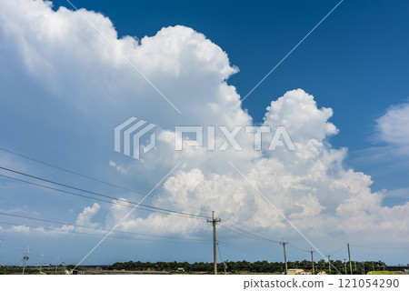 View of utility poles with blue sky and white clouds as a background. 121054290