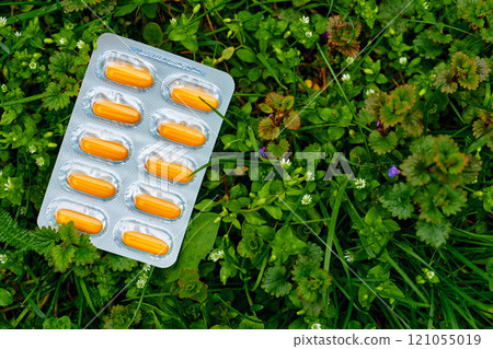 Orange pills in blister on green grass meadow Orange pills in blister on green grass meadow 121055019