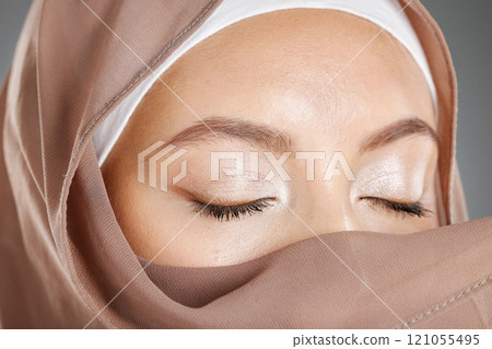 Closeup of a beautiful Muslim woman covering her beauty with her scarf and showing shimmery eyeshadow. Face of a stunning muslimah closing her eyes and showing perfect eye makeup look with a hijab Closeup of a beautiful Muslim woman covering her beauty with her scarf and showing shimmery eyeshadow. Face of a stunning muslimah closing her eyes and showing perfect eye makeup look with a hijab 121055495