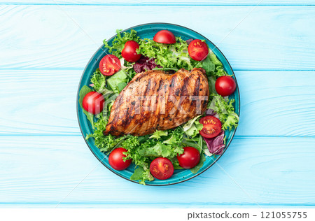 Grilled chicken breast ( fillet ) with lattuce salad and cherry tomatoes . Top view 121055755
