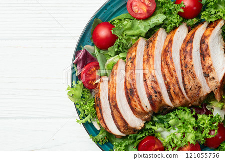 Grilled chicken breast ( fillet ) with lattuce salad and cherry tomatoes . Top view 121055756