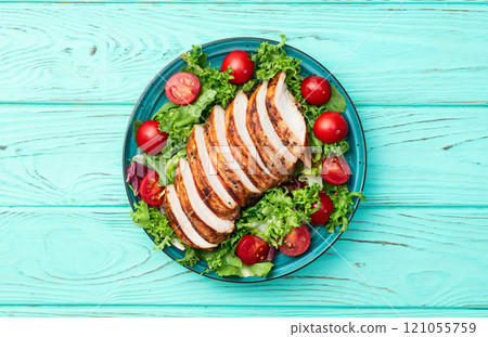 Grilled chicken breast ( fillet ) with lattuce salad and cherry tomatoes . Top view 121055759