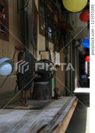 Treadle sewing machine in front of a dressmaking shop 121055886